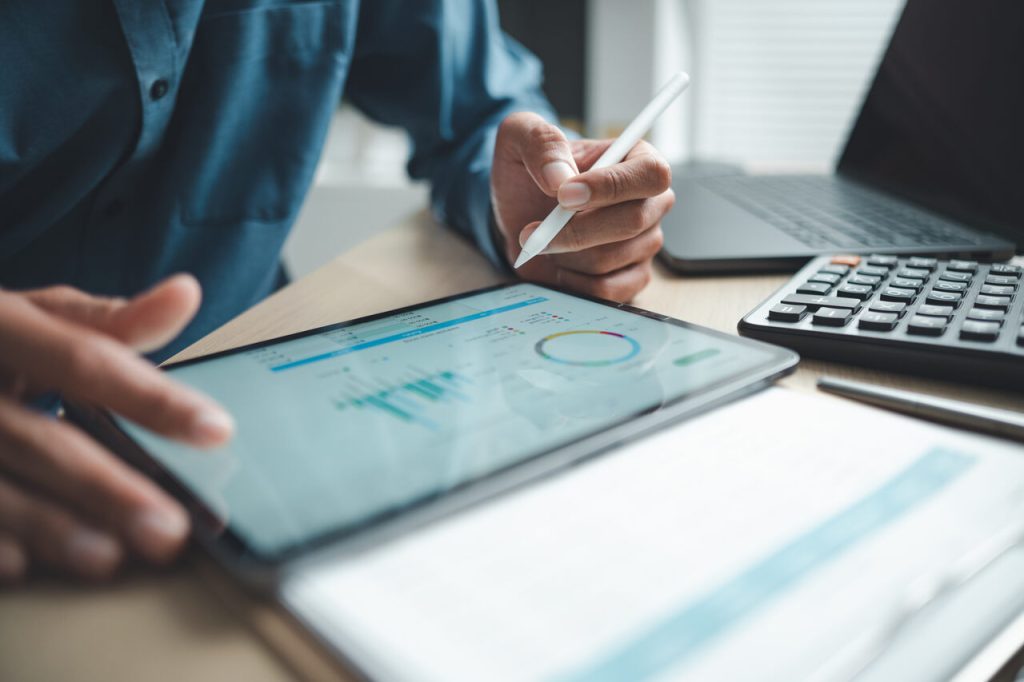 Profissional analisando dados financeiros em tablet com gráficos e indicadores de desempenho