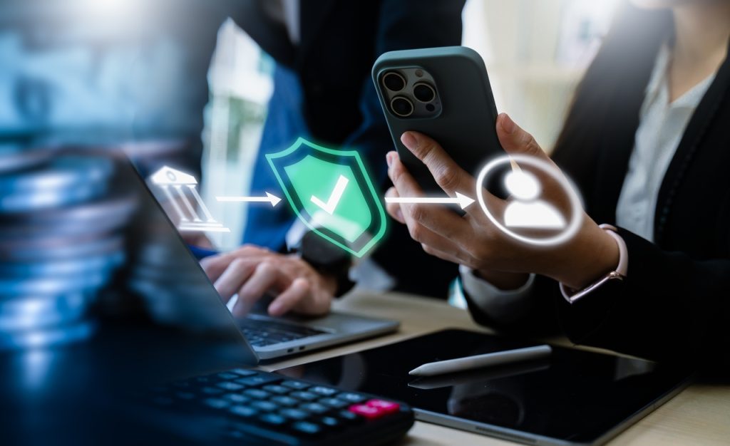 Profissional utilizando smartphone e notebook em ambiente corporativo com elementos visuais de segurança e validação digital relacionados à renovação de certificado digital.