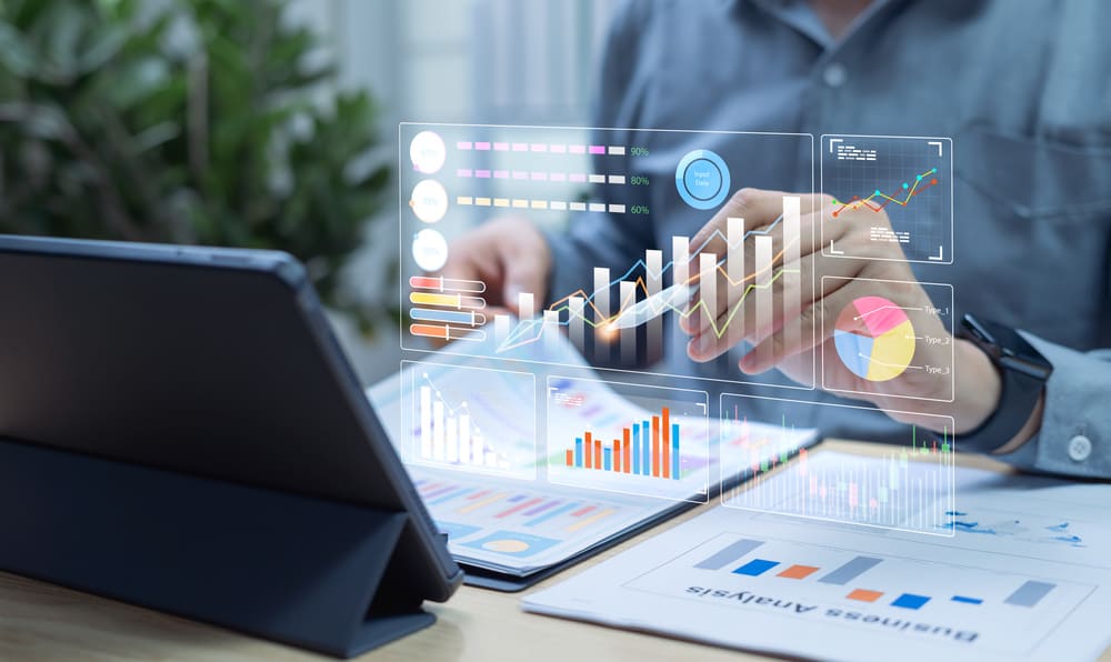 Profissional analisando gráficos financeiros em tablet e relatórios para elaboração da DRE com indicadores de desempenho