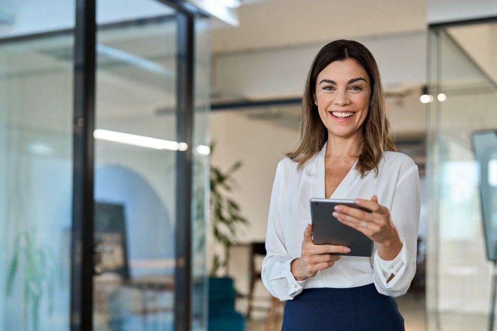Gestora de RH utilizando tablet em ambiente corporativo moderno, simbolizando a aplicação da tecnologia em recursos humanos nos processos de recrutamento e gestão de pessoas.