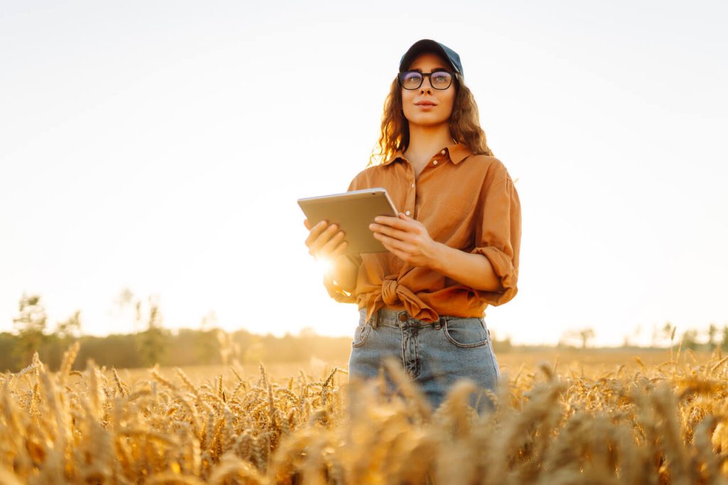 Profissional do agronegócio utilizando tablet para monitorar operações em campo e apoiar a gestão da agroindústria.