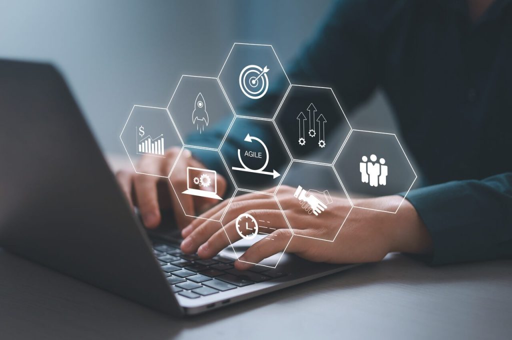 Profissional utilizando software PLM em notebook com ícones digitais representando product lifecycle management e gestão do ciclo de vida do produto na indústria