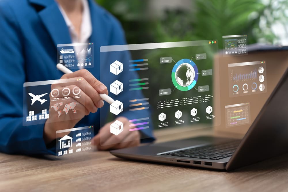 Pessoa utilizando notebook com interface digital de logística, exibindo gráficos, rotas e dados operacionais integrados em um sistema TMS SaaS.