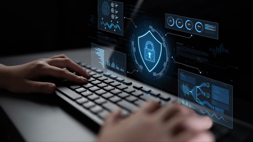 Profissional digitando em teclado com interface digital de segurança exibindo gráficos e cadeado, ilustrando práticas de privileged access management para proteção de acessos críticos.