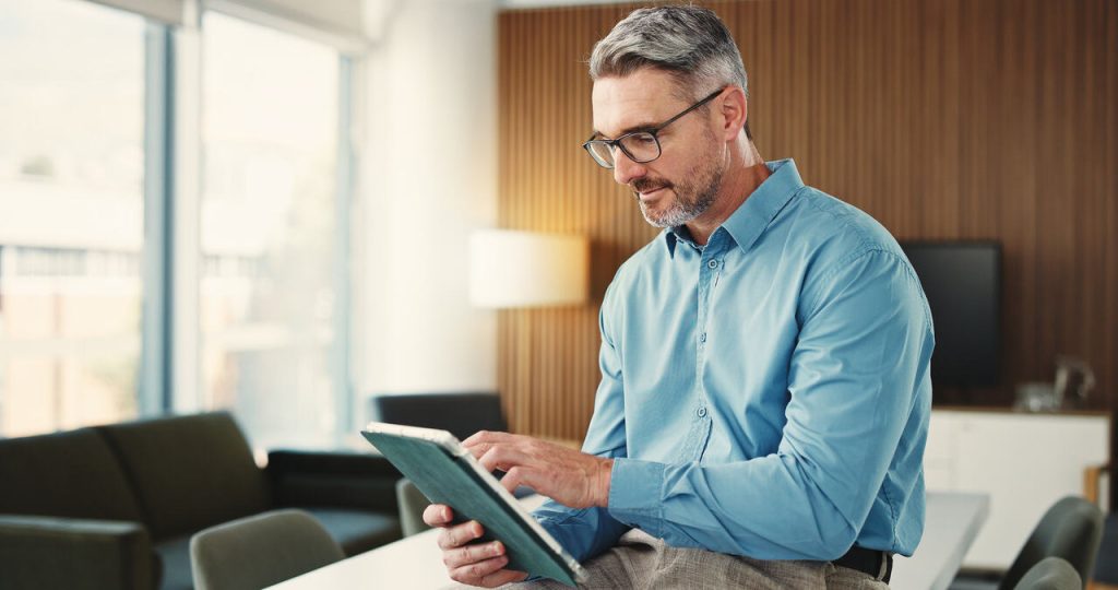 Profissional utilizando tablet em escritório corporativo moderno e iluminado, representando gestão estratégica de tecnologia e consultoria da TOTVS para empresas.