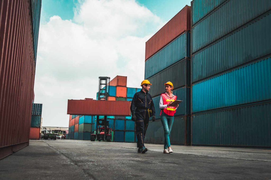 Profissionais da logística realizando inspeção e monitoramento de containers em terminal de cargas portuário
