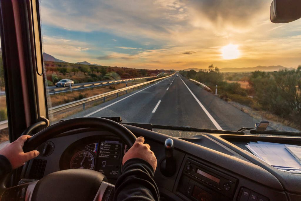 Motorista profissional dirigindo caminhão em rodovia durante operação logística de transporte