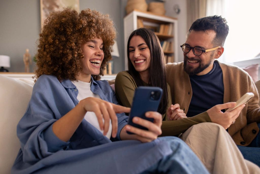 Grupo de Millennials utilizando smartphones em ambiente residencial, representando comportamento digital, consumo online e interação tecnológica no cotidiano