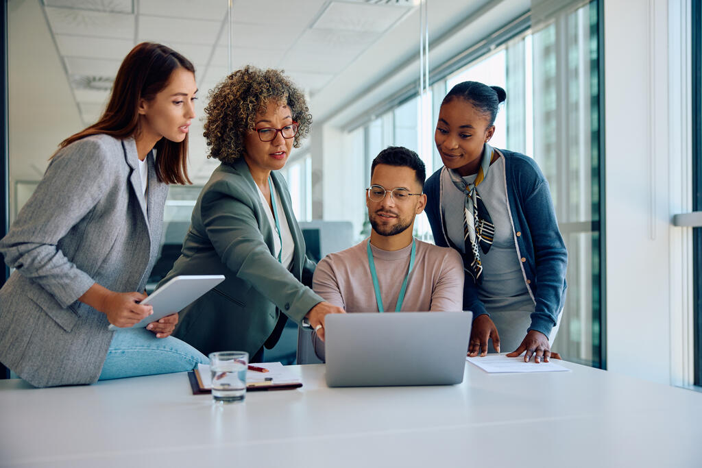 mulher apontando para notebook enquanto a equipe discutindo sobre jornada de trabalho