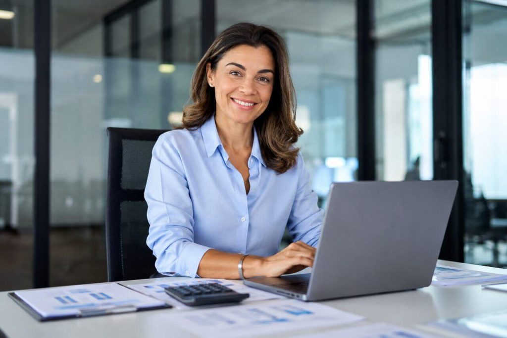 Gestora financeira analisando indicadores e cobranças em notebook para gestão de pagamentos e controle financeiro empresarial com DDA.