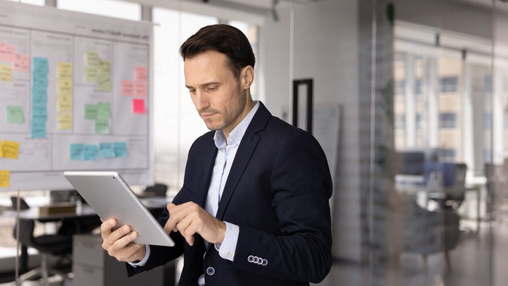 Executivo utilizando tablet em ambiente corporativo para análise de dados com inteligência artificial para empresas